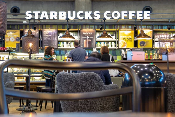 Emberek megrendelése kávé és a cookie-kat a Starbucks belül Lyon Saint Exupery International airport, miközben vár eltölteniük két járat között. Repülőtér kávé és pihenjen - szerkesztői. — Stock Fotó