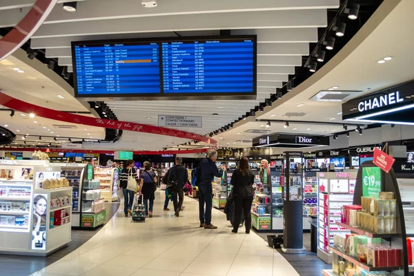 Viajantes em Saint Exupery aeroporto, Lyon, movendo-se através das ilhas de uma loja duty free dentro do terminal, durante suas transferências de avião . — Fotografia de Stock