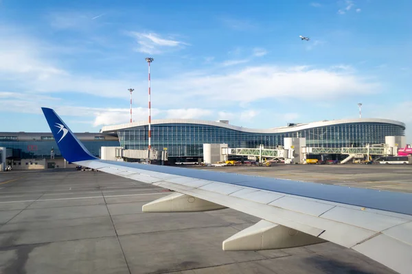 Pesawat Blue Air mendarat di Bandar Udara Internasional Henri Coanda, bersiap untuk keberangkatan, menghadap ke bangunan bandara utama. Perjalanan dan terbang - editorial . — Stok Foto