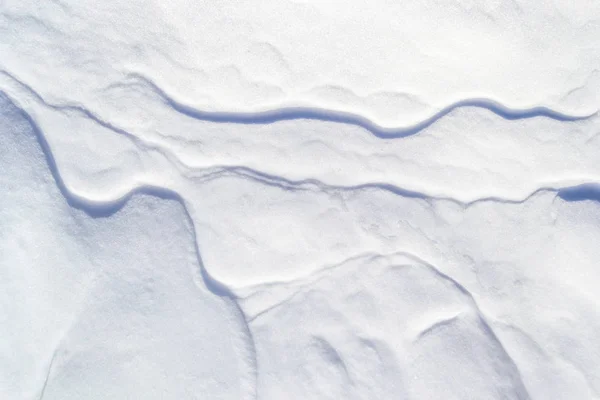 Χιόνι με υφή φόντο με λεπτές μικρές αυλακώσεις που πηγαίνουν απέναντι σαν φλέβες. Απλή, μινιμαλιστική, αφηρημένη ταπετσαρία χειμερινού φόντου με διακριτές γραμμές σκιάς. — Φωτογραφία Αρχείου