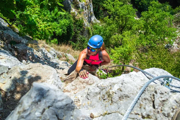 Adventurous, courageous woman climber on a via ferrata route called \