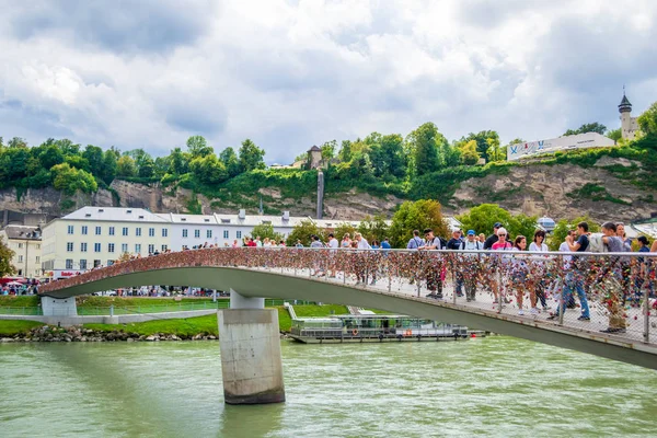 Маркартштегский мост с замками любви и туристами, пересекающими его и фотографирующими в Зальцбурге, Австрия. Летний городской пейзаж . — стоковое фото