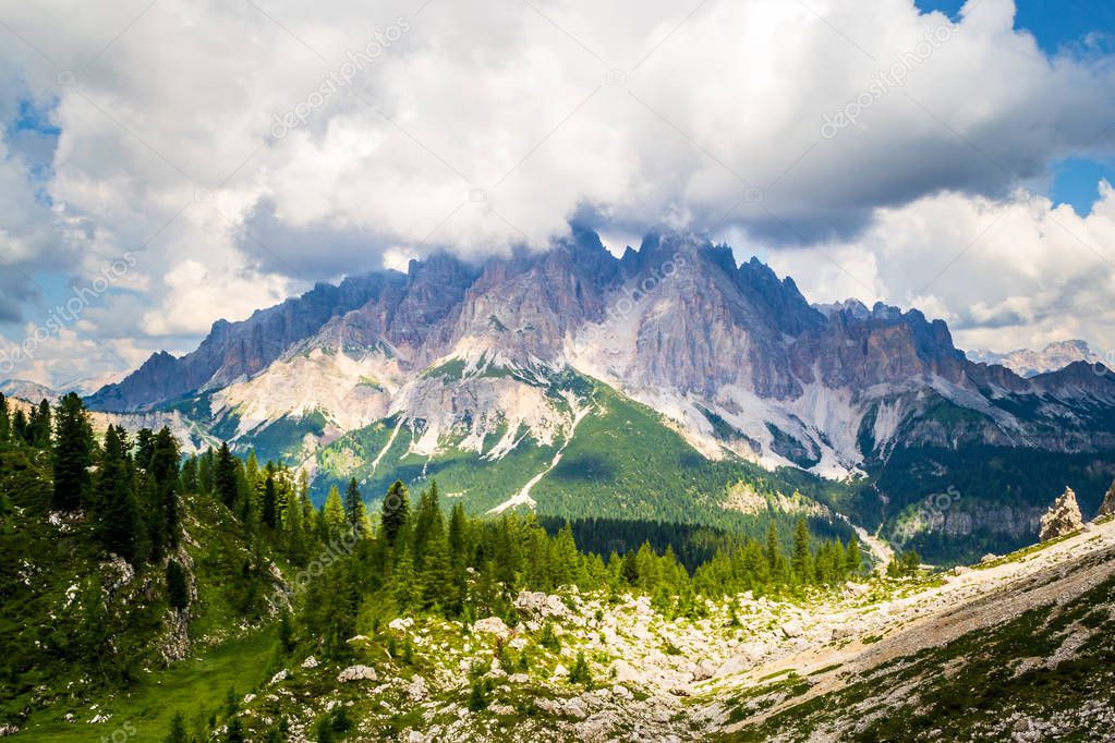 Monte Cristallo in Dolomites mountains, Italy, with big white clouds, as seen from a hiking trail towards Forcella Marcoira and Lago di Sorapis, during Summer. Breathtaking scenic views in the nature.