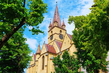 Saint Mary Lutheran Katedrali (Catedrala Evanghelica C.A. Sfanta Maria) Sibiu, Romanya, gözcü kulesine doğru görünüm, yeşil ağaçlar tarafından çerçeveli, parlak gün ışığında. Popüler turistik nokta.