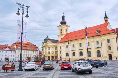 Sibiu, Romanya, 27 Mayıs 2019: büyük meydanda, Brukenthal, Belediye Binası ve kutsal Trinity Roma Katolik Kilisesi ile, dramatik gökyüzü.