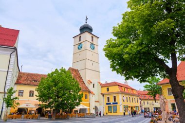 Sibiu, Romanya-27 Mayıs 2019: Sibiu 'daki Council Tower (Turnul Sfatului), ana büyük meydandan, yeşil ağaçlarla bulutlu gününde görüldü. Hermannstadt, Romanya popüler turistik dönüm noktası.