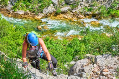 Hırvatistan'da Ferrata üzerinden, Cikola Kanyonu. Genç kadın arka planda Cikola nehri turkuaz renkleri ile, orta zorluk klettersteig tırmanma.