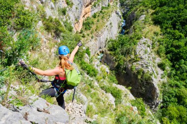 Kask takan ve ferrata dişli ile genç kadın turist, parlak, güneşli bir günde, Cikola kanyon, Hırvatistan, Cikola nehri doğru, mesafe elini işaret ediyor. Dağcılık ve macera konsepti