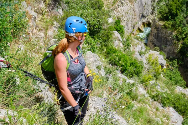 Woman with helmet and via ferrata gear looking down towards Cikola river, in Cikola canyon, Croatia, on a bright, sunny day. Adventure concept.