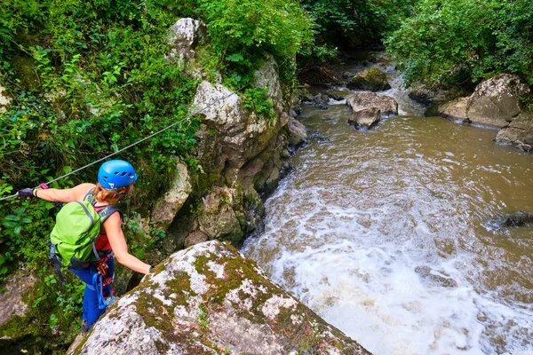 Tureni / Copaceni Gorge Paraul Racilor üzerinde bir kablo bölümü geçerken ferrata dişli ile kadın turist, Romanya, küçük bir şelale yanında. İlkbahardan Sonbahara kadar popüler doğa destinasyonu.