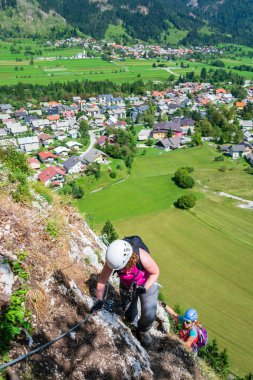 Slovenya'nın Mojstrana köyünün üzerindeki Grancisce tepesinde ferrata yolunda iki kadın yüksekte. Dikey.