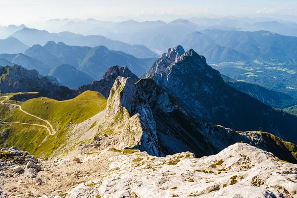 Βουνοκορυφογραμμή στο Μάνκαρτ (πέρασμα) στα σύνορα μεταξύ Σλοβενίας και Ιταλίας, διαιρώντας τις Ιουλιανές Άλπεις και τις ιταλικές Άλπεις-θερμό φως ηλιοβασιλέματος με ορεινές στρώσεις στο πίσω μέρος. — Φωτογραφία Αρχείου