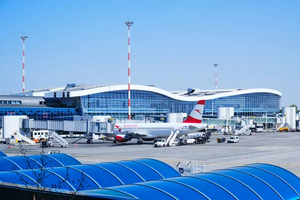 Otopeni, Romanya - 15 Eylül 2019: Austrian Airlines uçağı, Henri Coanda Uluslararası Havaalanı Bükreş'te mavi gökyüzüyle açık bir günde biniş köprüsüne demirledi.