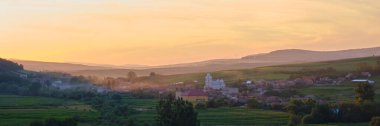 Romanya 'nın Petrestii de Jos kentindeki tepelerle çevrili Transilvanya köyünün günbatımı manzarası - Turda Vadisi' nden manzara.