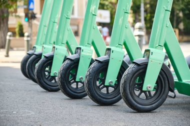 Yeşil-mavi elektrikli scooterlar, şehirlerde daha temiz ve modern bir alternatif ulaşım seçeneği. Ön tekerleri kapatın..