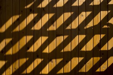 Gölge ve ışık. Dekoratif ızgara ile ahşap bir duvarda Güneş ışığı