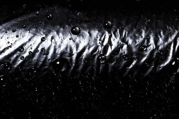 Σταγόνες νερού σε μαύρο φόντο. Μαύρο πολυαιθυλένιο. Απομίμηση μαύρου Eco-Leather. — Φωτογραφία Αρχείου