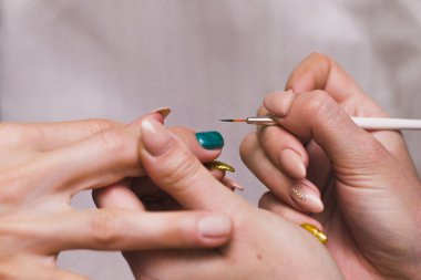 Bir kadın turkuaz jel cilası ile çivi boyar. Evde salon prosedürleri. Close