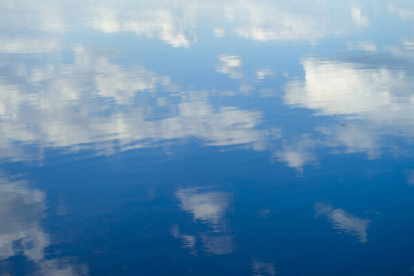 reflection of clouds in the river. Ripples on the surface of the water