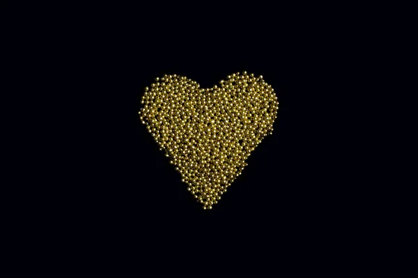 heart from edible gold sprinkles on a black background