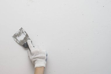 Çalışan bir alet, beyaz bir duvarın arka planında duran bir spatula, sıva işi. Oyuncak duvarlar kendi elleriyle.