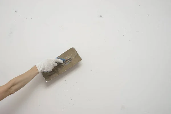 woman hand with metal big spatula, to equalize the plaster filler on the wall. Putty walls with their own hands.