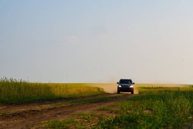 Kızıl geçit bir ülke toprak yolda toz bulutu yükseltir. Yeşil çayır boyunca yol.