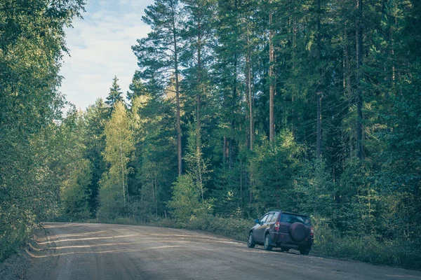 El coche está de pie en el lado de un camino de tierra país en el bosque. Paisaje con árboles altos. Borde del bosque a principios de otoño. —  Fotos de Stock