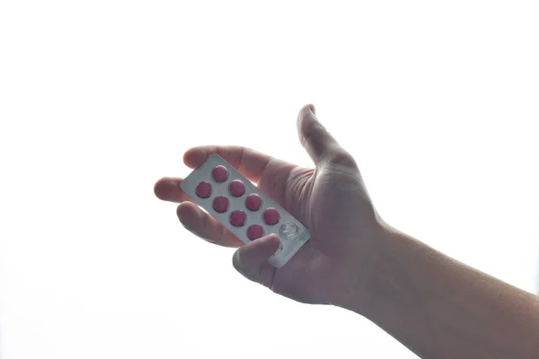 Manlig hand håller ett blister med rosa piller. Isolera på en vit bakgrund. — Stockfoto