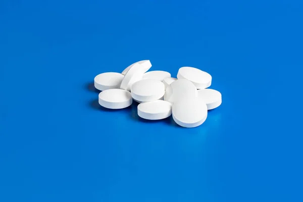 Bianco pillole rotonde sparse sfondo blu, caoticamente sparsi . — Foto Stock