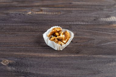 Koyu ahşap arka planda kağıttan bir kek fincanında ceviz parçası.