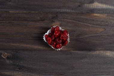 Koyu ahşap bir arka planda, kağıt kek bardağında kurutulmuş kiraz servisi..