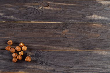 Kabuğu soyulmuş fındıklar karanlık bir masaya saçılmış. Tahta arkaplanda boşluk kopyala.