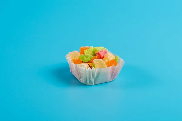 青い背景の紙マフィンカップに砂糖漬けの果物の一部 — ストック写真