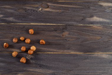 Kabuğu soyulmuş fındıklar karanlık bir masaya saçılmış. Tahta arkaplanda boşluk kopyala.