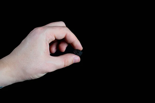 Пальцы Держат Один Черный Изюм Черном Фоне — стоковое фото