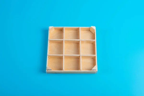 A small, wooden box with storage trays. Empty box on a blue background.