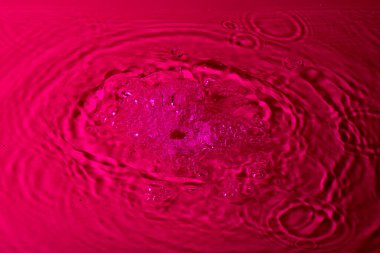 Kırmızı arka planda bir damla su. Soyut duvar kağıdı