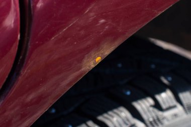 Arabanın vişne rengi paslanmış. Aşınma izleri var. Arka kanat