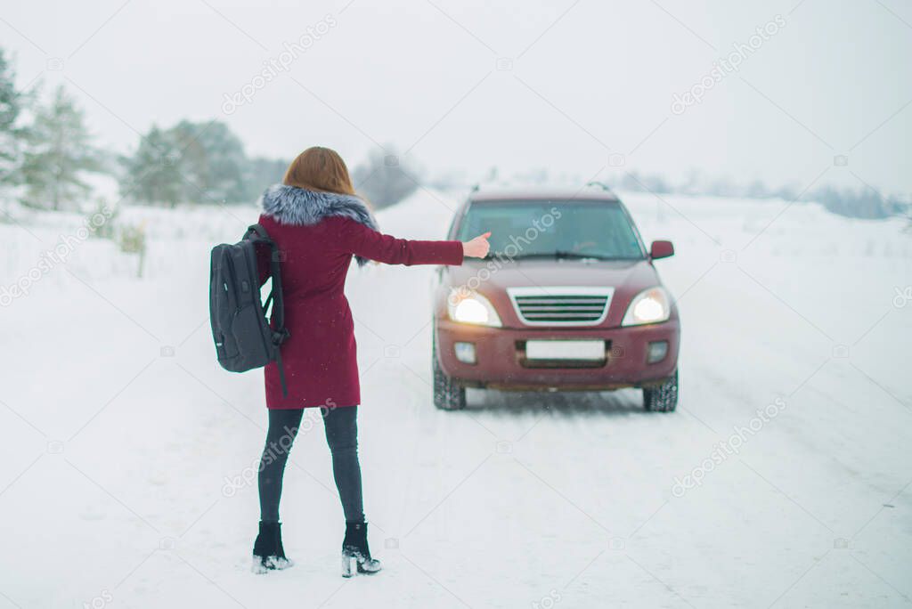 Girl on winter road with the car asking for help.