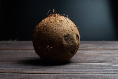 Tam hindistan cevizi ve kopyalama alanı. Eski bir masanın koyu ahşap yüzeyinde, yazı için yeri olan büyük kahverengi bir hindistan cevizi değil..