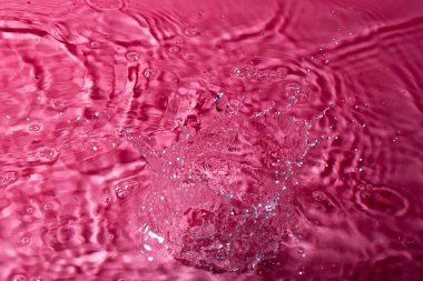 Kırmızı arka planda bir damla su. Soyut duvar kağıdı