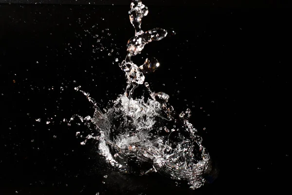 Salpicadura de agua clara sobre fondo negro aislado. — Foto de Stock