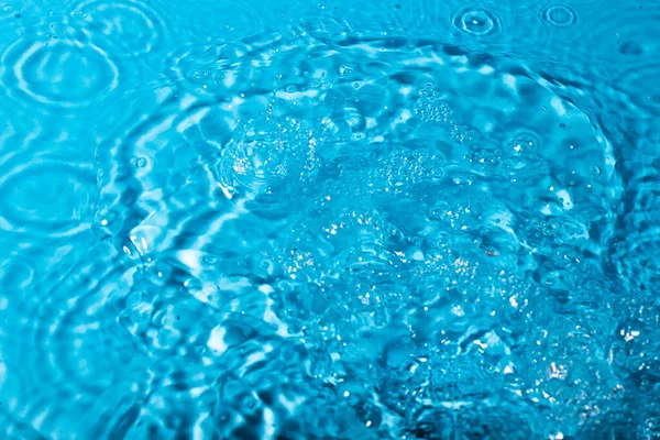 Wasserspritzer auf blauem Hintergrund. Abstrakte Tapete — Stockfoto
