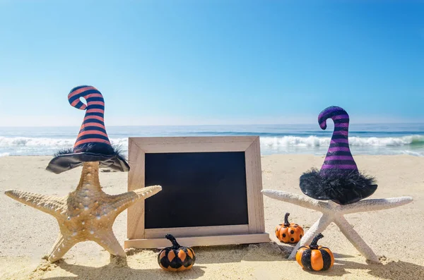 Halloween background with starfishes in the witch\'s hats on the sandy beach near the ocean