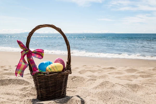Coelho da Páscoa com ovos coloridos na praia do oceano — Fotografia de Stock