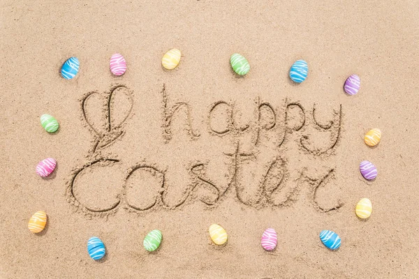 Happy easter lettering background with eggs on the sandy beach — Stock Photo, Image