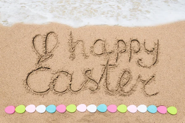 Fröhliche Ostern Schriftzug Hintergrund mit Eiern am Sandstrand — Stockfoto