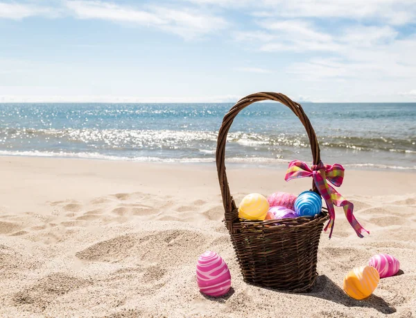 Paashaas met eieren van de kleur op het strand van de Oceaan Stockfoto