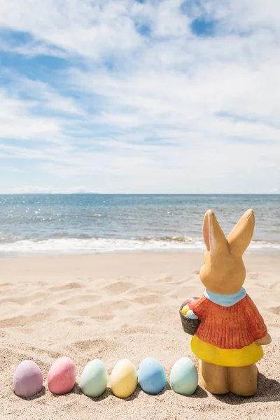 Spiaggia sfondo di Pasqua con coniglietto e uova di colore Fotografia Stock